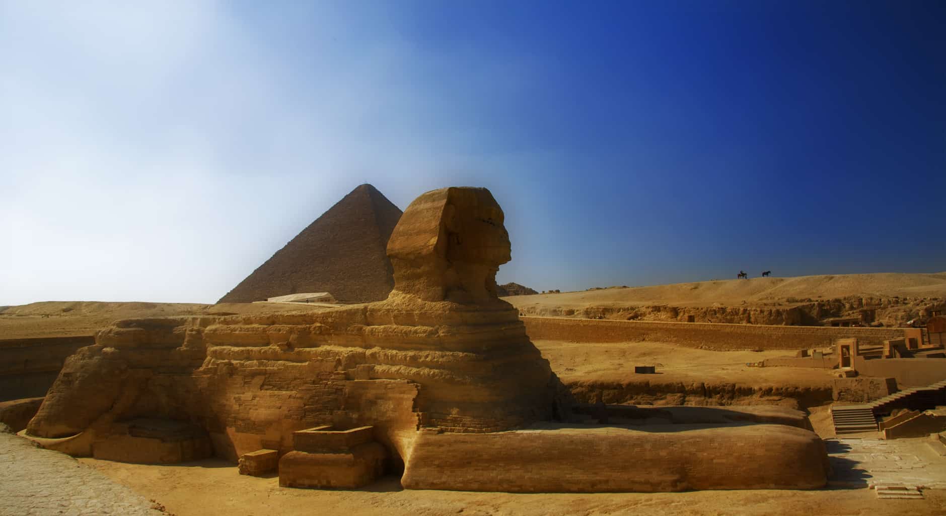 Cairos Great Sphinx stands proudly with a pyramid under a clear blue sky.