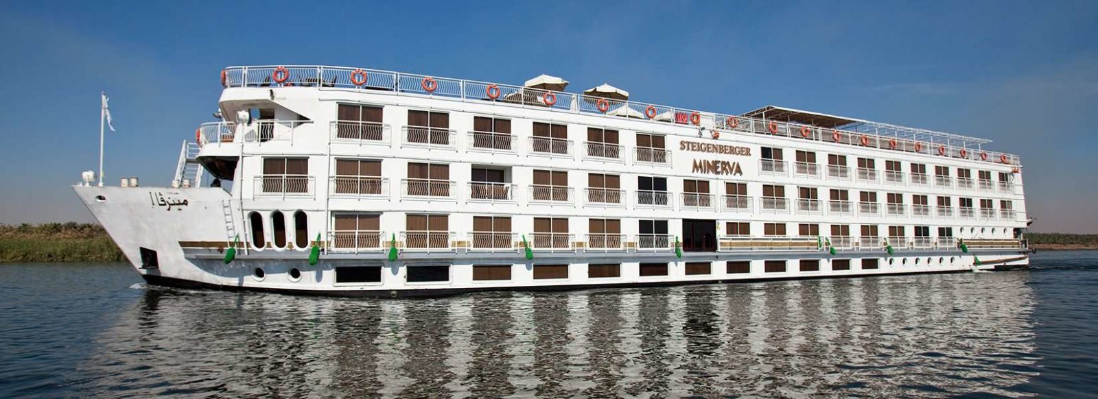 Top benefit: a large white river cruise ship gliding on calm water under a clear blue sky.