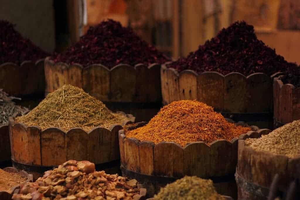 Experience Egyptian street food with assorted spices in wooden barrels at a market.