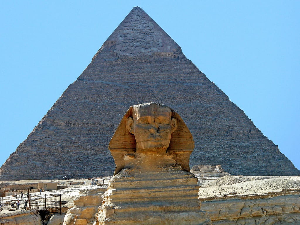The Great Sphinx and Pyramid of Giza glow under Egypts clear blue sky.