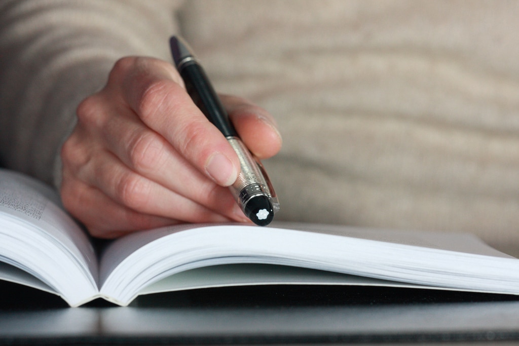 Hand holding a pen over an inspiring book for your Egyptian holiday.