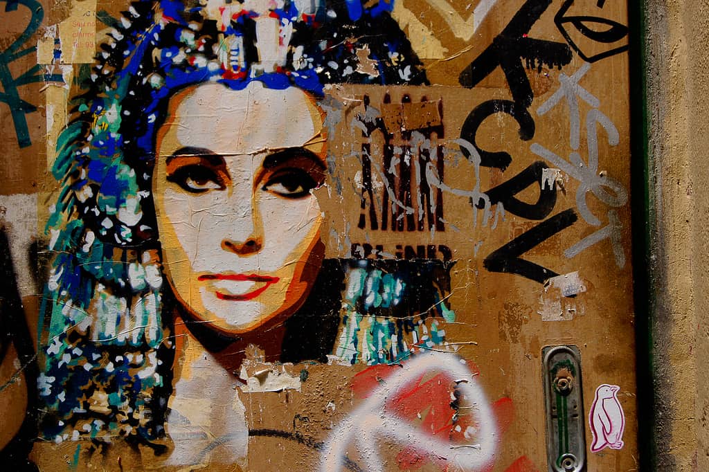 Nile-themed street art on a graffiti-covered wall with colorful embellishments.
