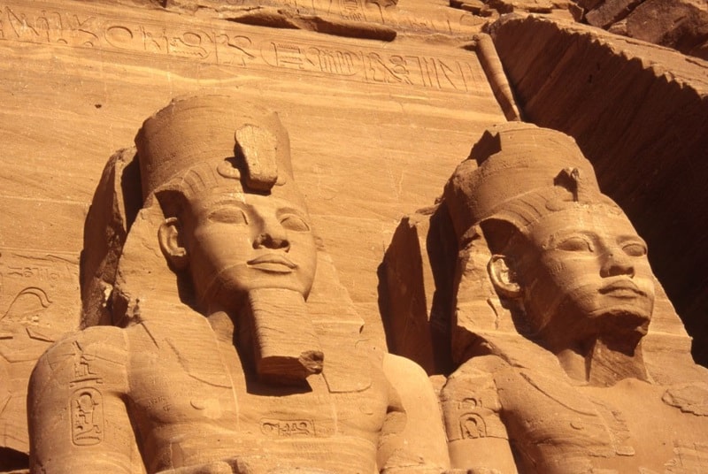 Ancient stone statues with headdresses bask under the Egyptian sun.