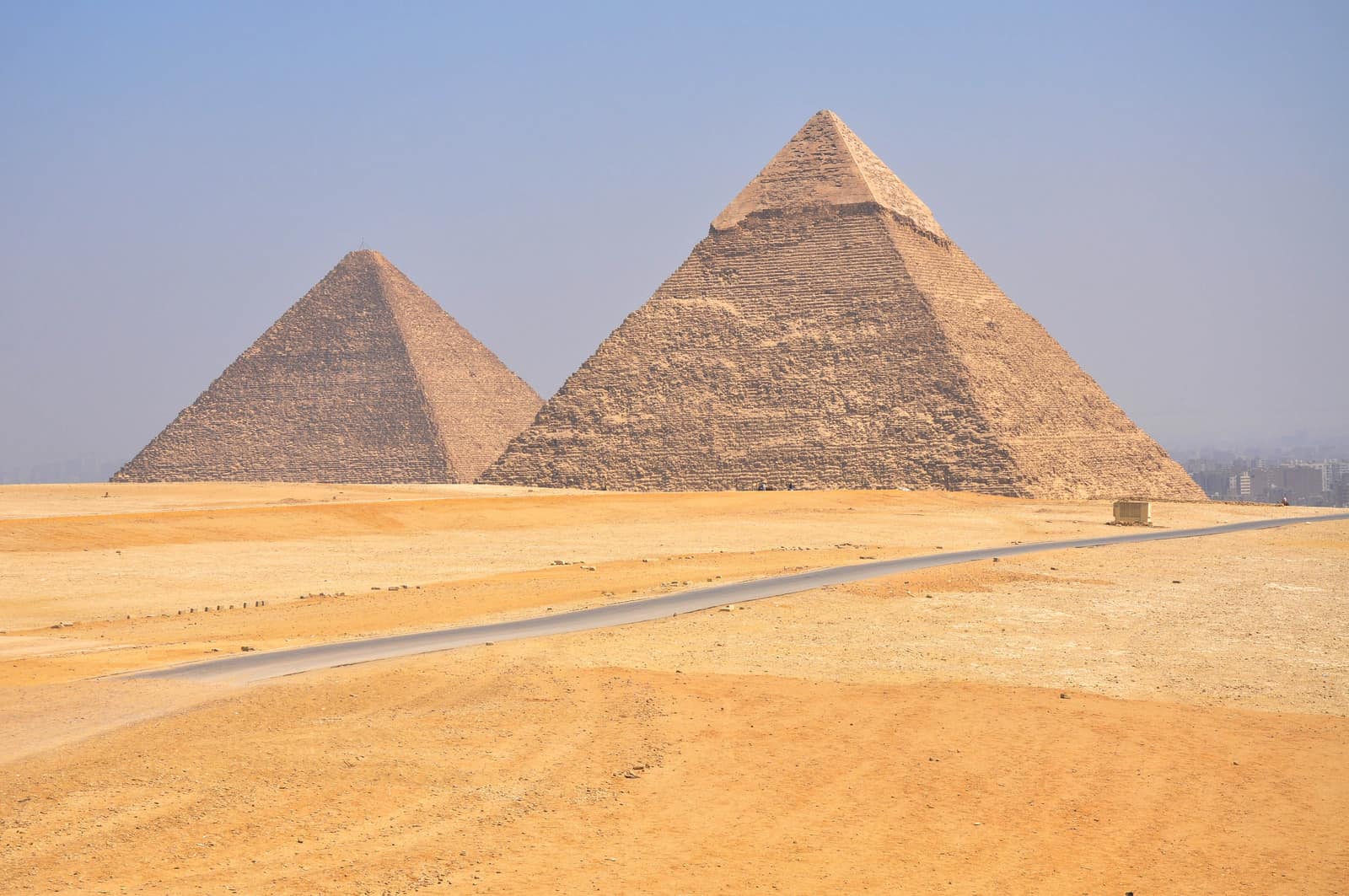 Two must-visit pyramids stand in a desert under a clear blue sky.