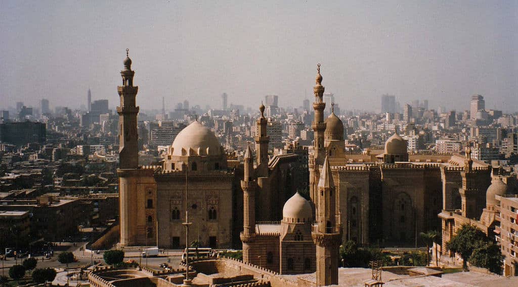 View of a mosque complex in Egypts expansive cityscape on a hazy day.