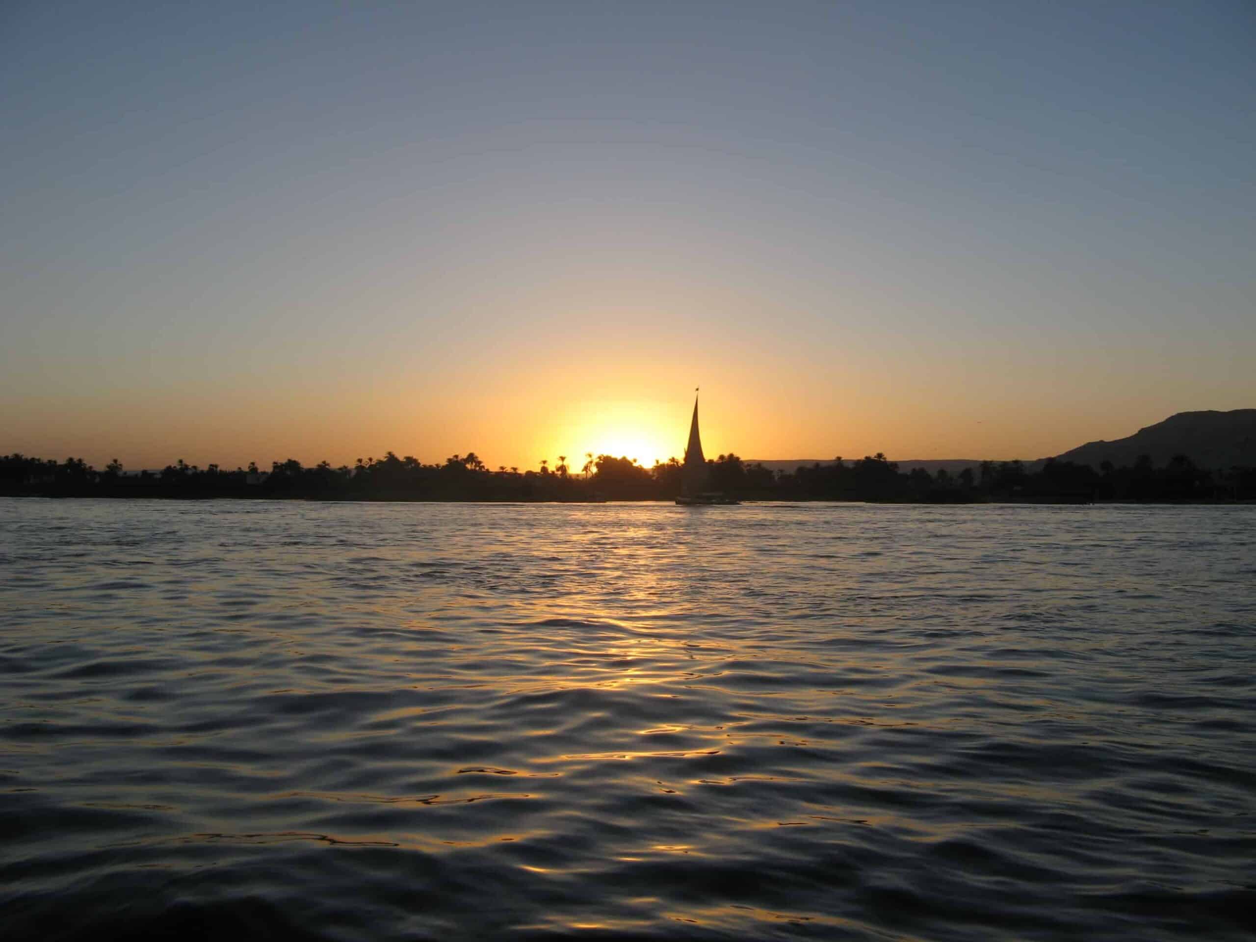 Sunset over a river, Ms Royal Esadoras silhouette against distant trees on the horizon.