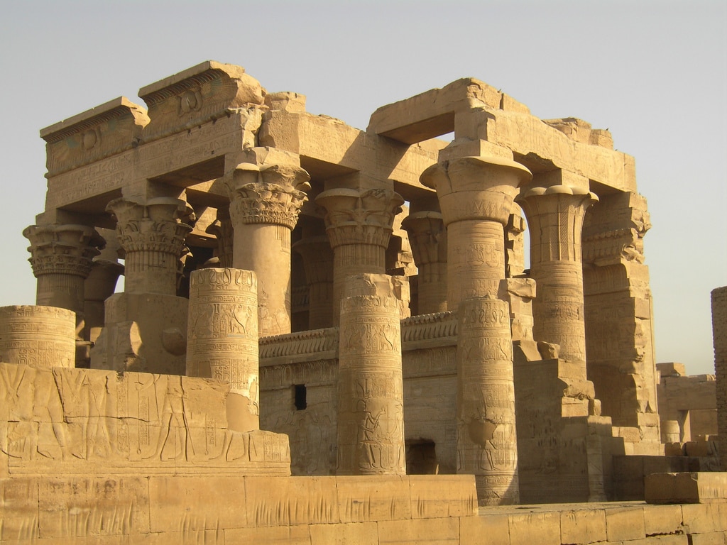 Ancient stone temple with carved columns on a Nile journey under a clear sky.