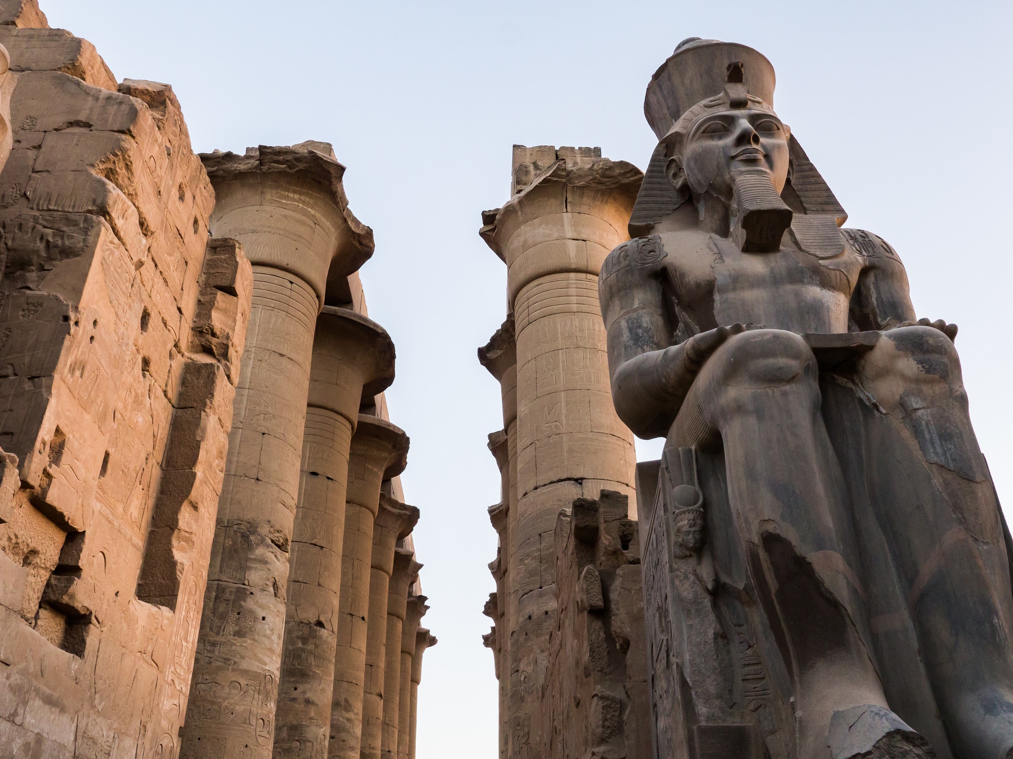 Ancient Luxors statue and columns at the temple, Egypt, under a clear sky.