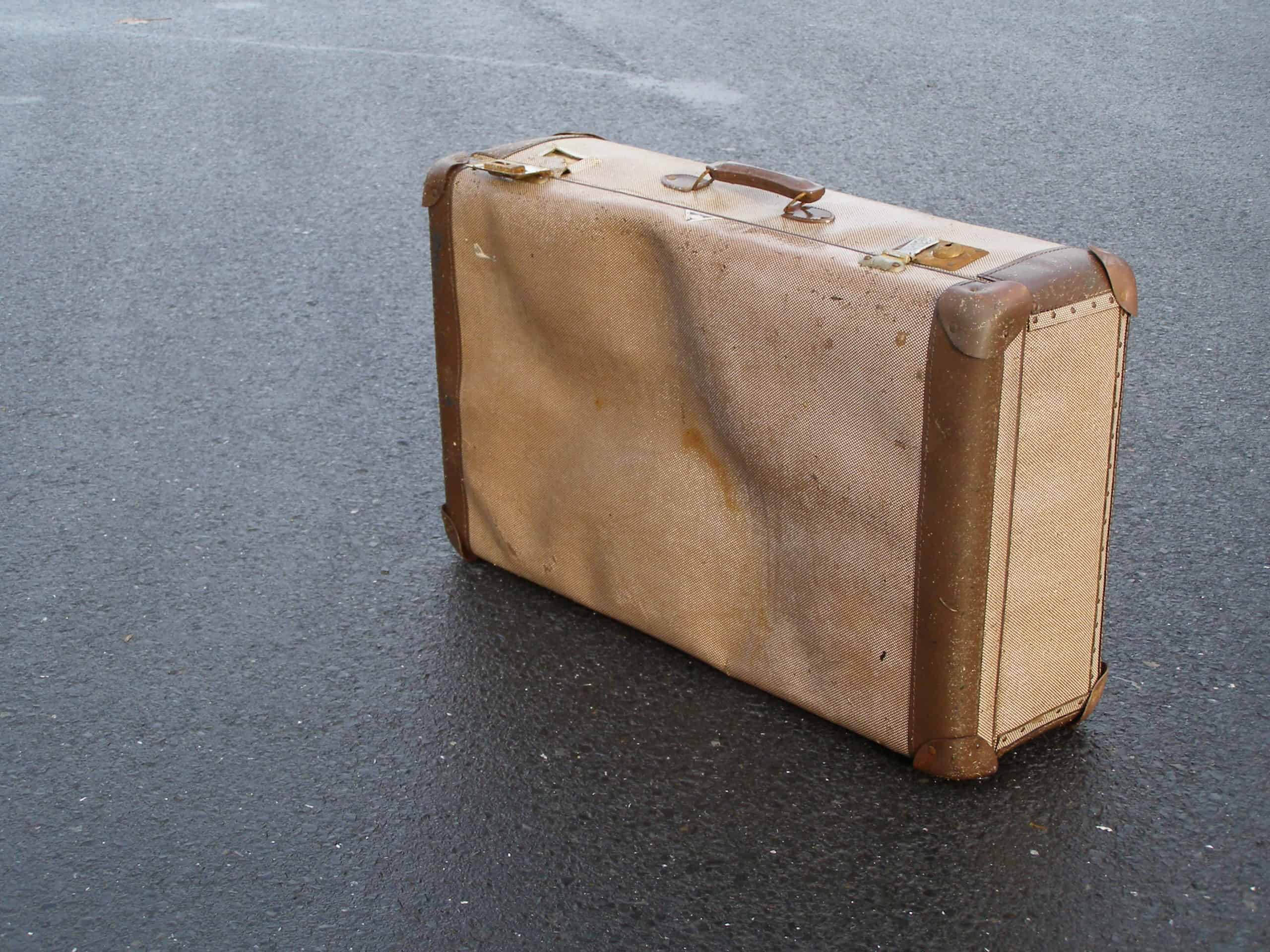 A worn suitcase sits on wet pavement, hinting at a Nile cruise adventure.
