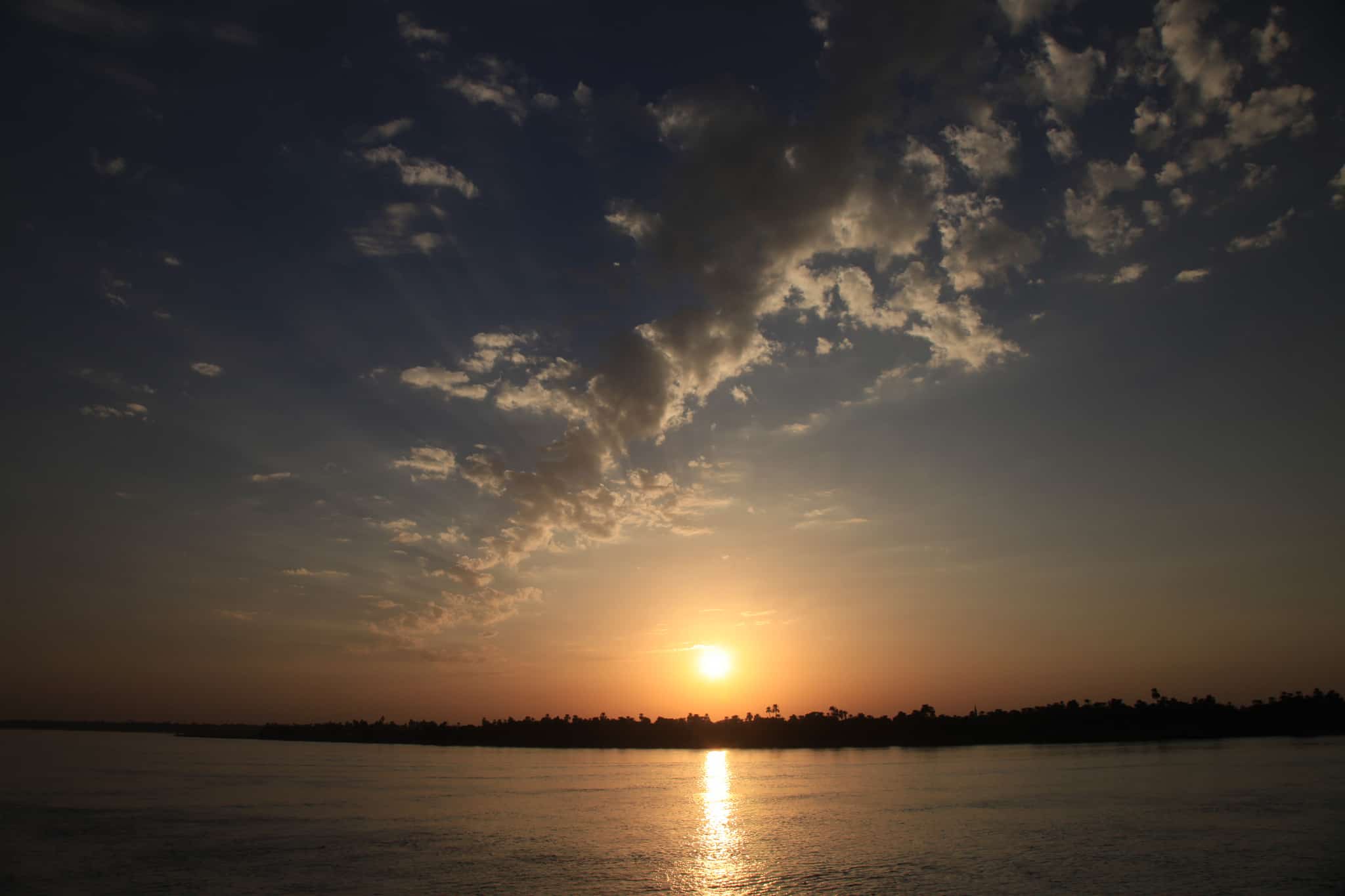 Sunset over the Niles calm water, a literary adventure in scattered clouds.