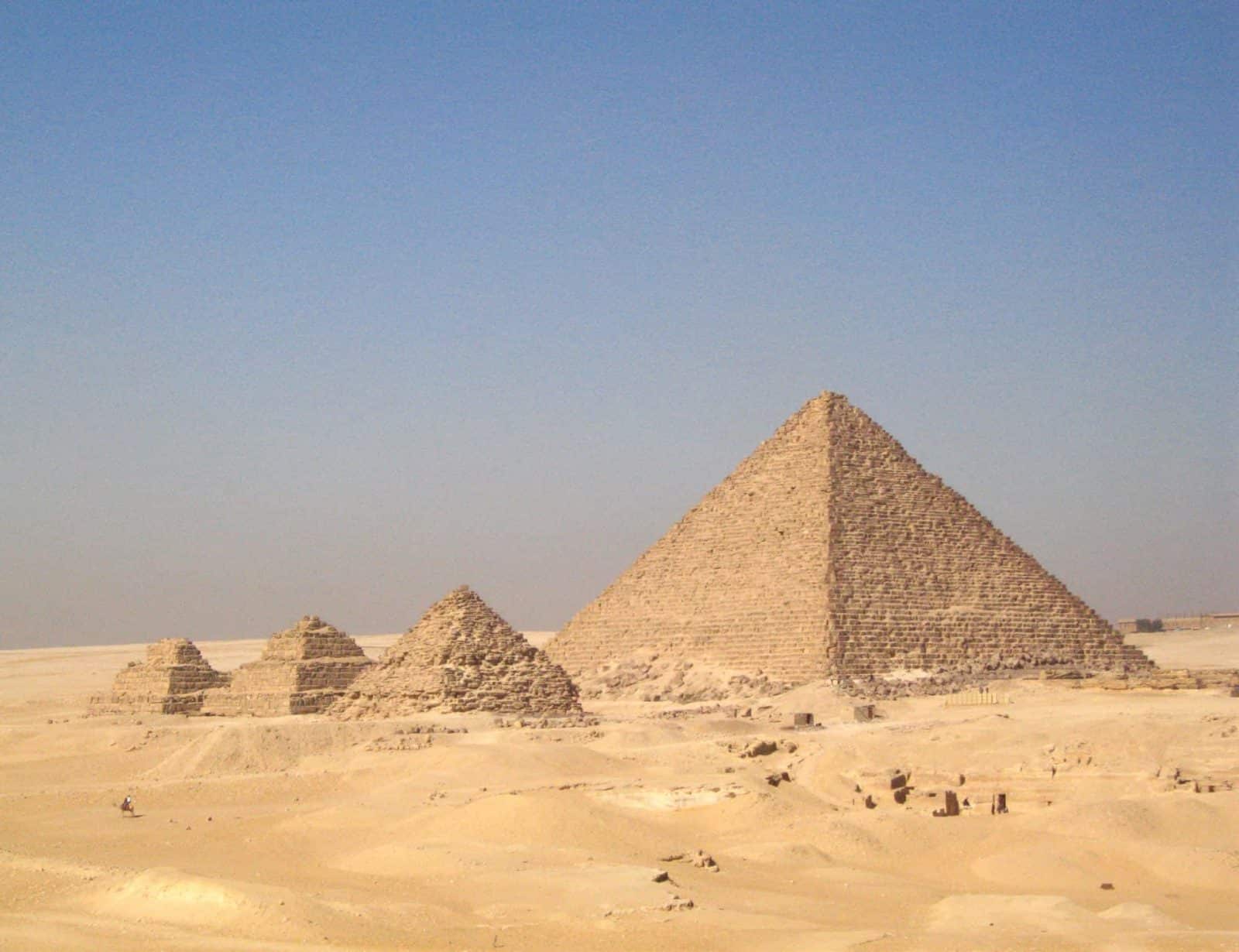 Pyramids in Cairos desert under a clear blue sky.
