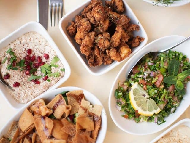 Assorted Middle Eastern dishes, fried chicken, salad, and dips on a Luxor-themed table.