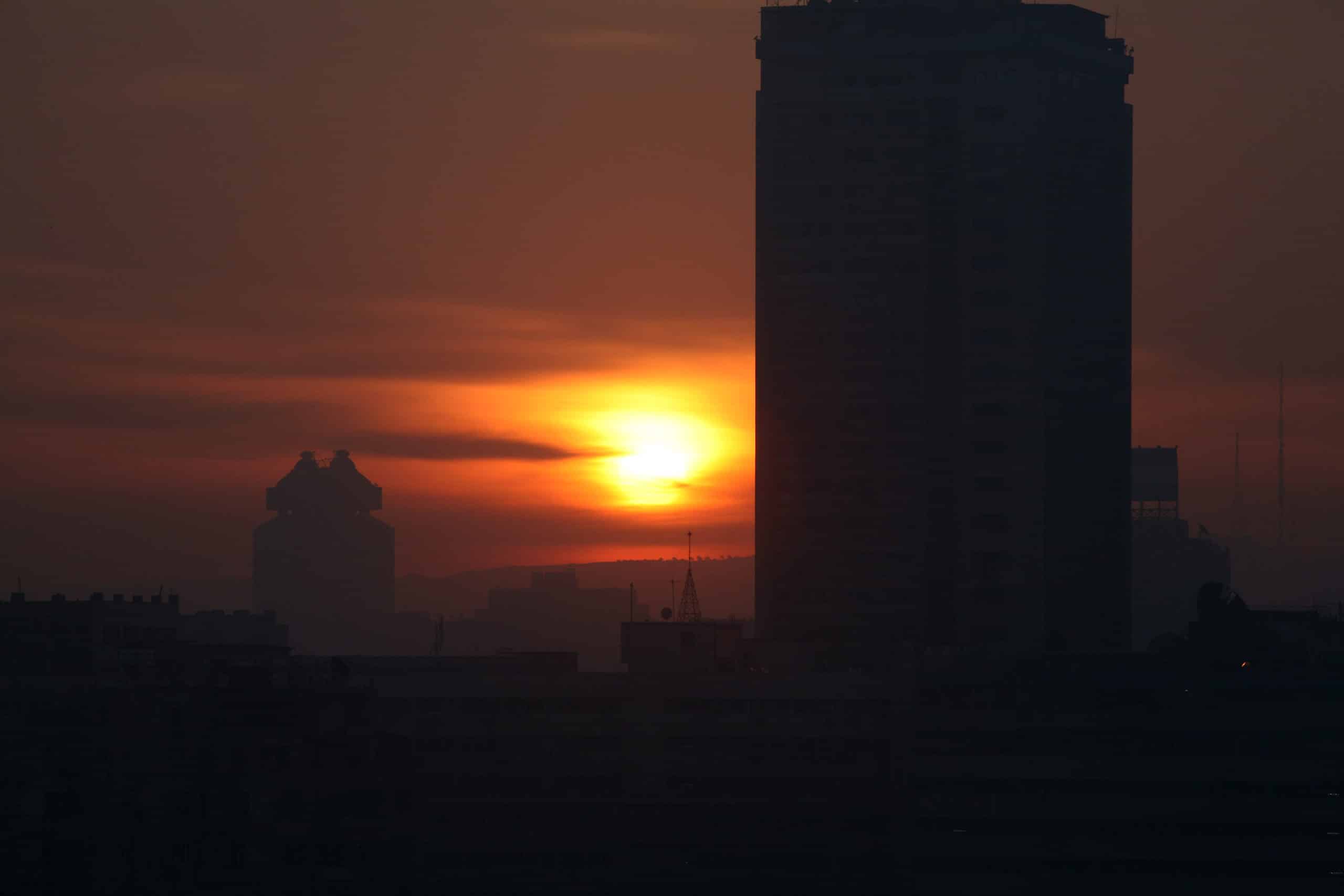Cairo skyline at night with sunset and dark building silhouettes in the foreground.