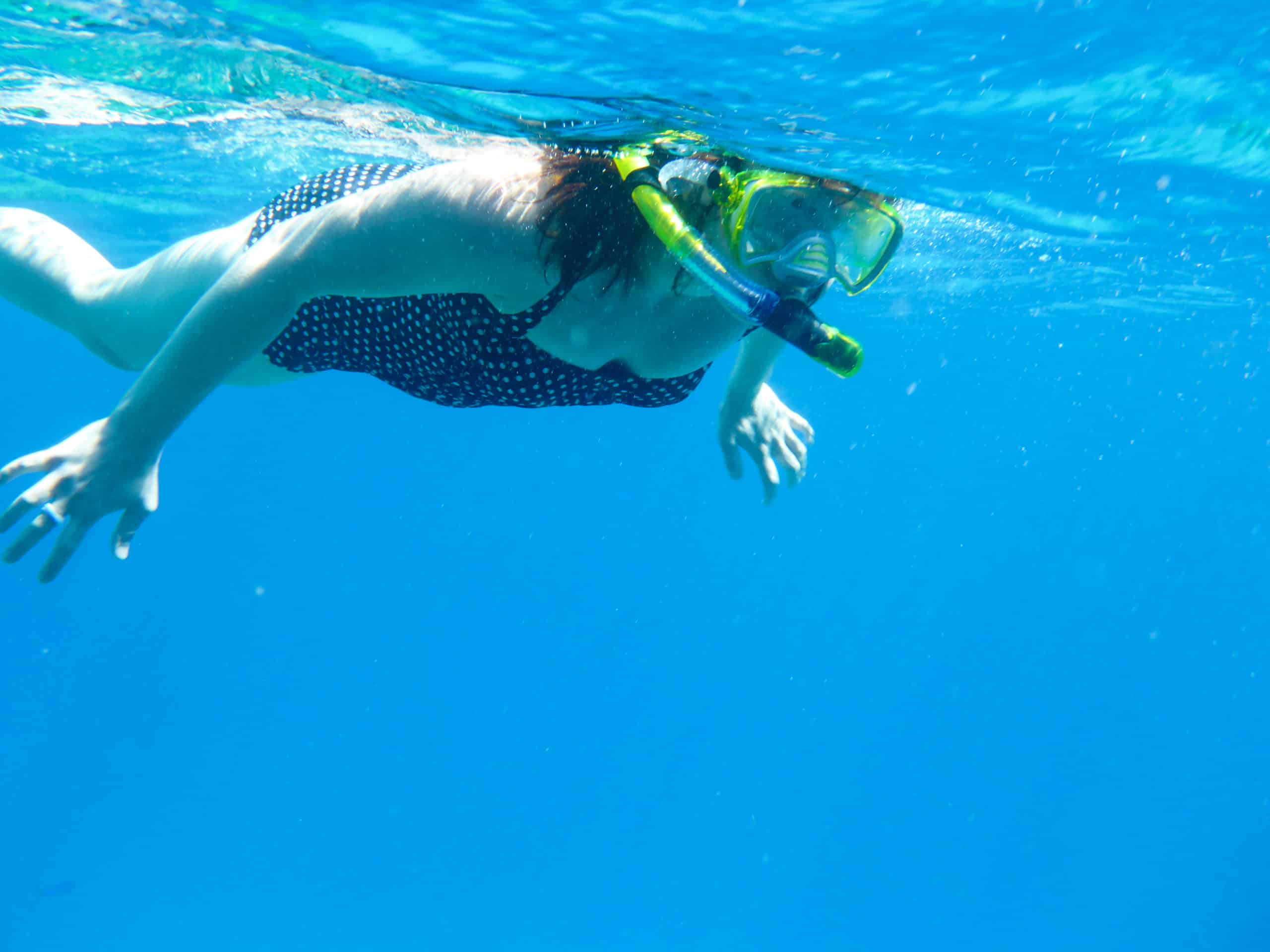 Person snorkeling in Sharm El Sheikhs clear blue water wearing a polka dot swimsuit and snorkel.