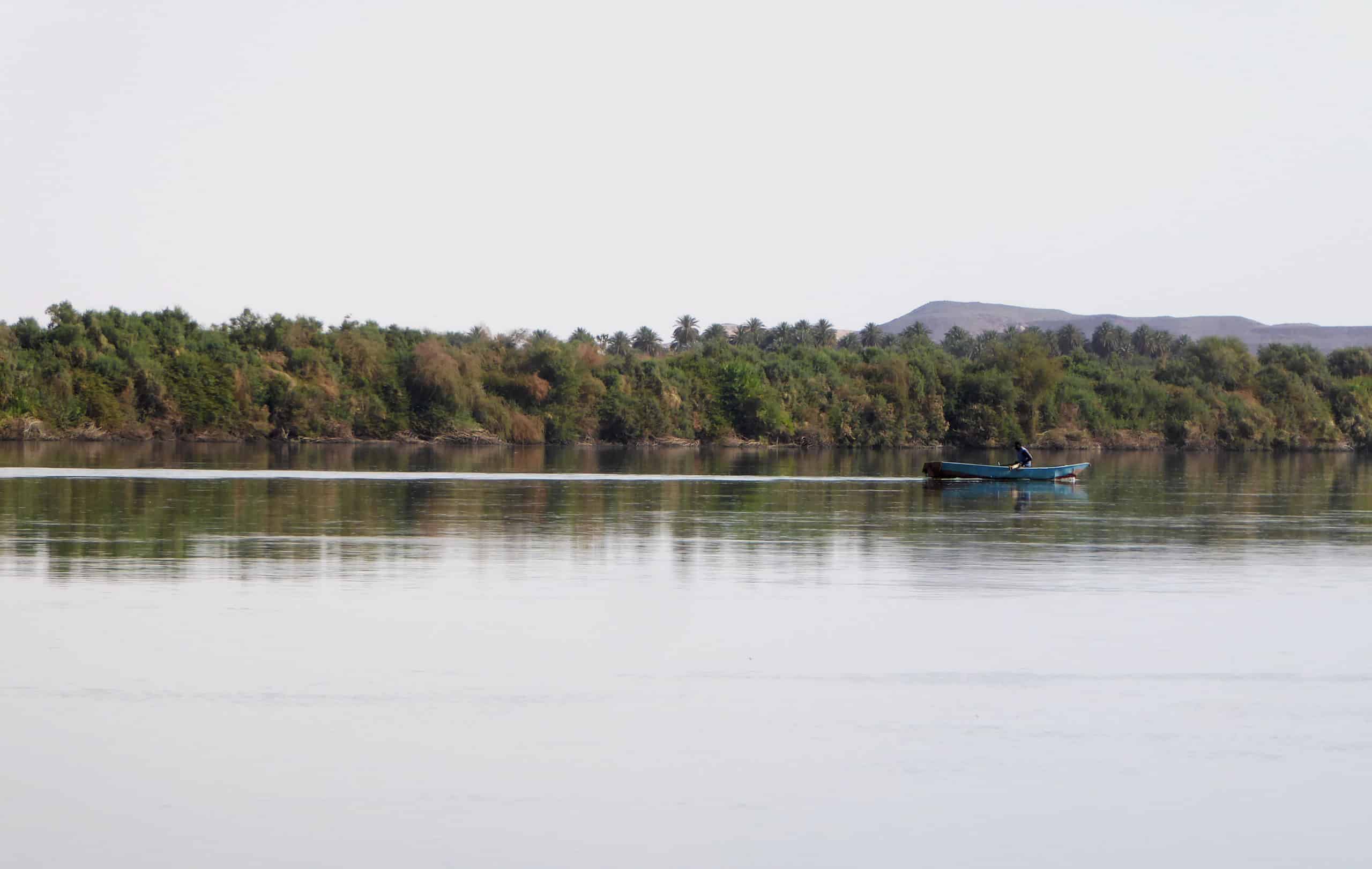A boat on the Nile with greenery lining its serene shoreline.