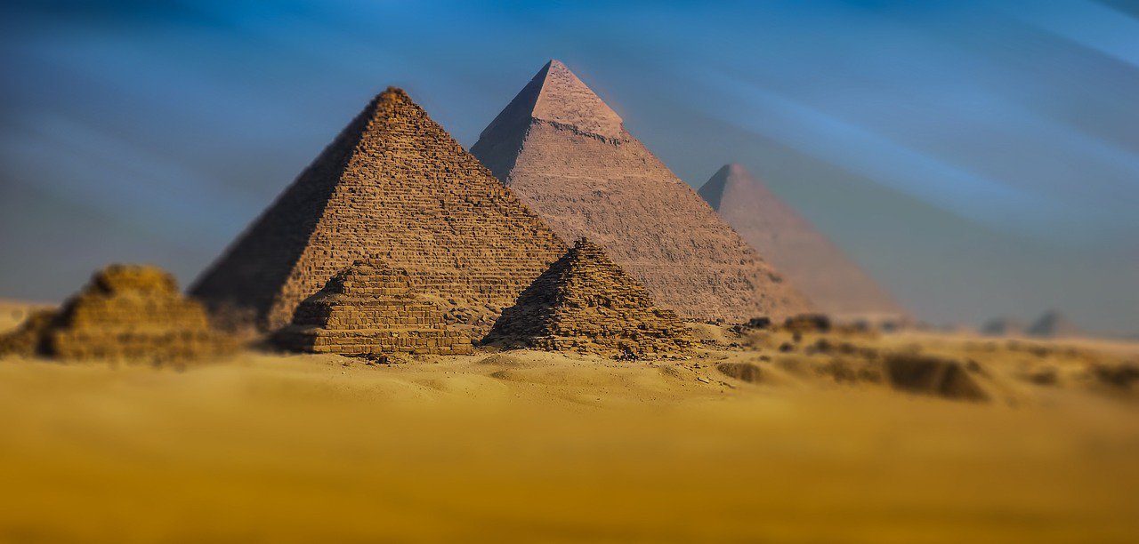 Ancient pyramids in Egypt under a clear blue sky in a sandy desert landscape.