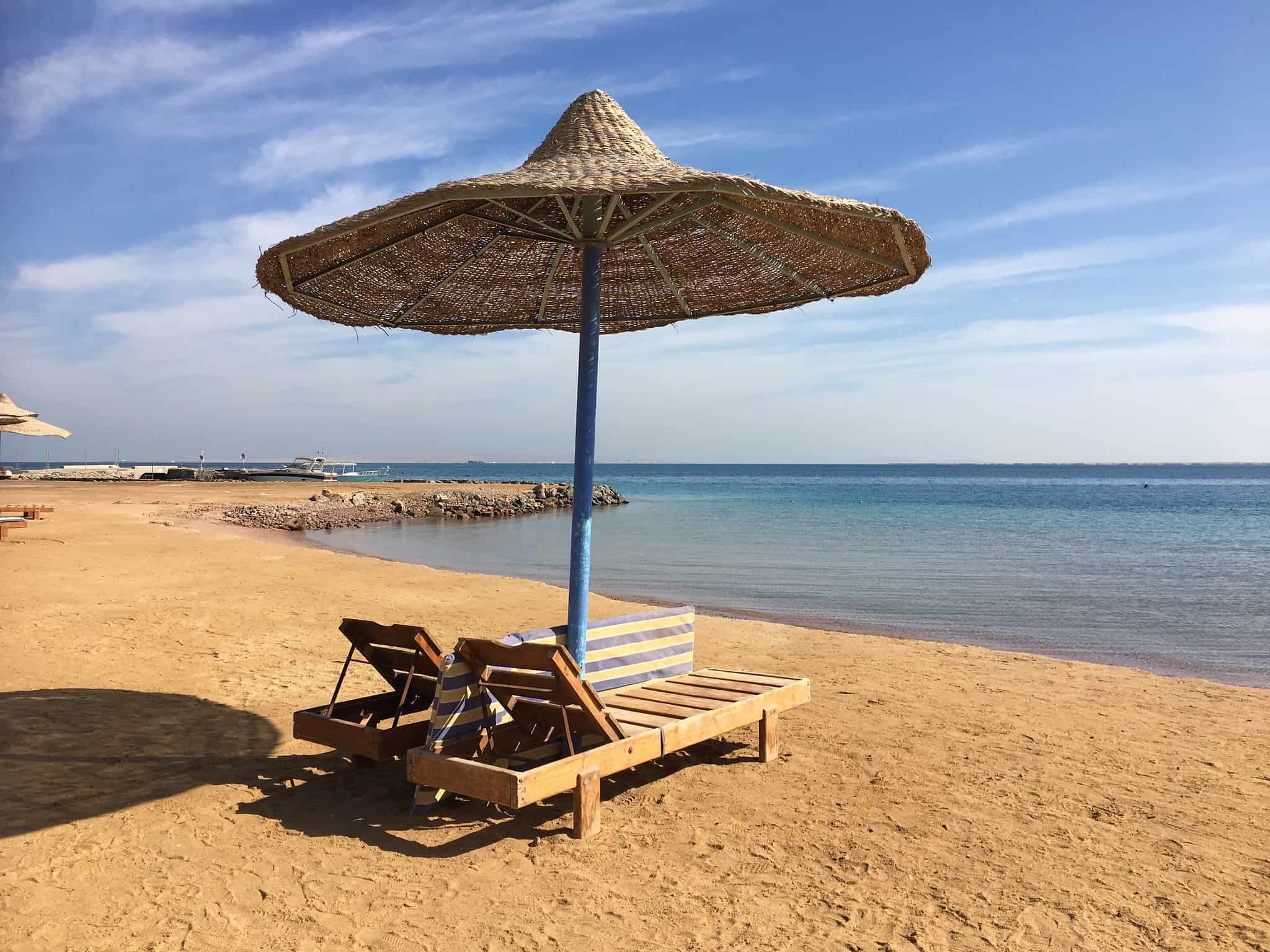 Lounge chairs beneath a straw umbrella, your oasis before a 14-night Nile cruise adventure.