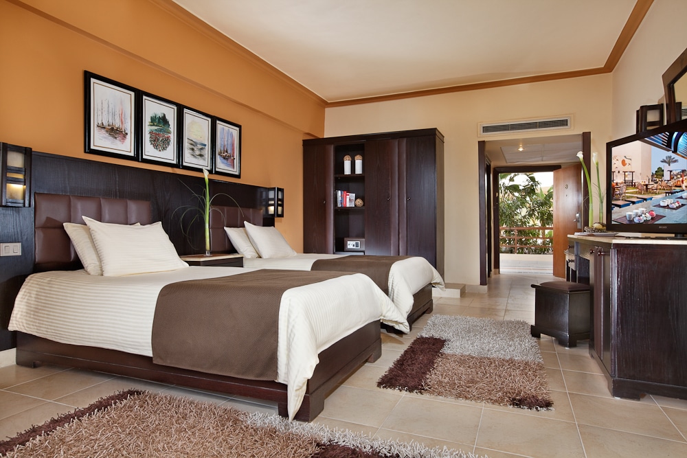 Royal Albatros Moderna room: two beds, TV, balcony, brown and white decor.