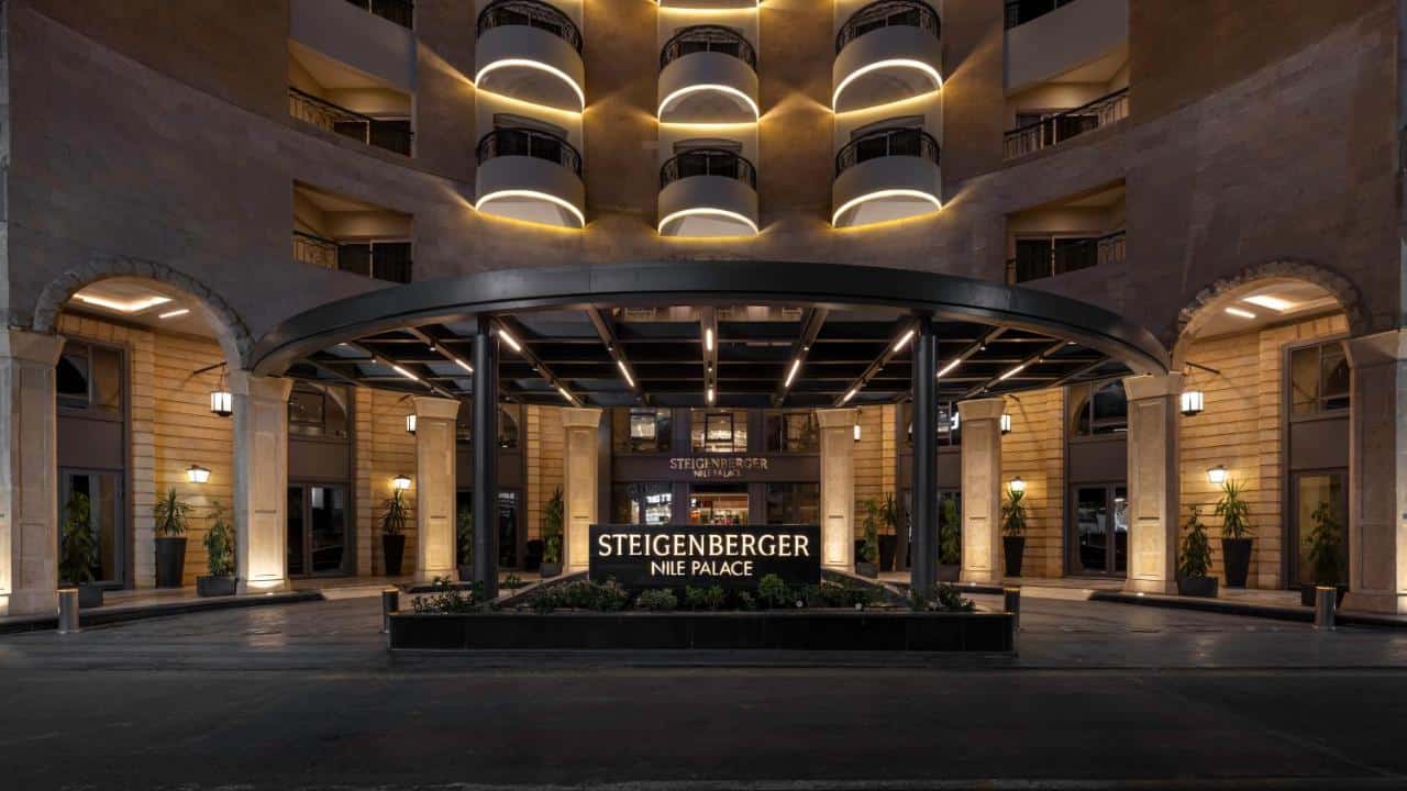 Illuminated sign at Steigenberger Nile Palace with balconies towering above.