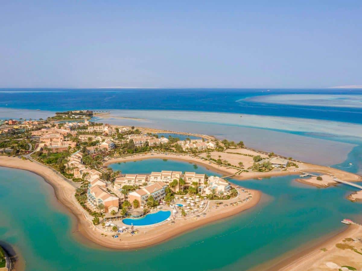 Aerial view of Mövenpick Resort El Gouna with lagoons and sandy beaches under a clear blue sky.