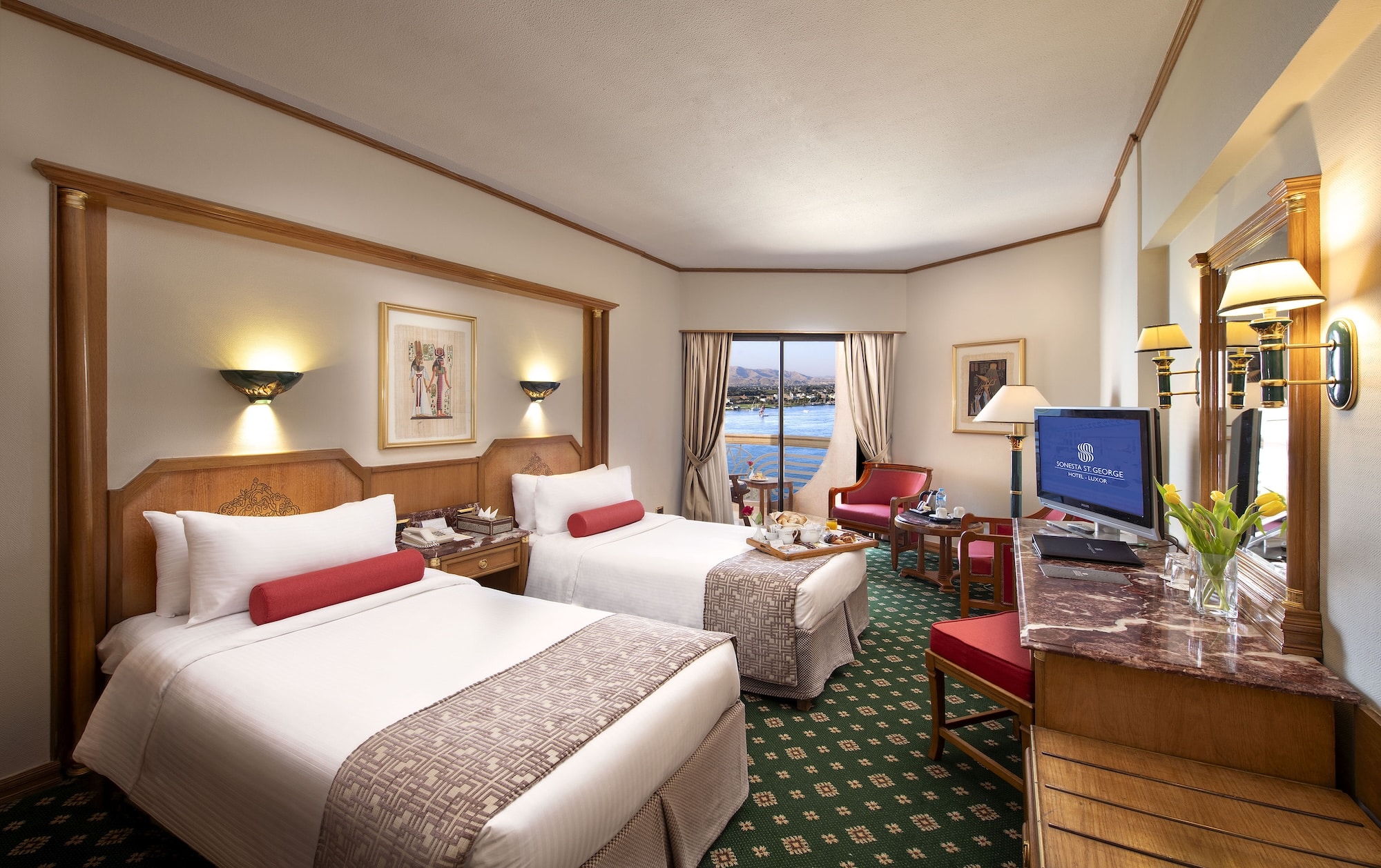 Sonesta St George Luxor room with two beds, window view, and desk with a TV.