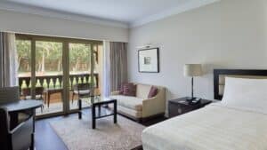 Marriott Mena House hotel room with a bed, sofa, and a balcony offering garden views.