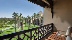 Balcony view of a garden with palm trees and the Marriott Mena House pyramid in the background.