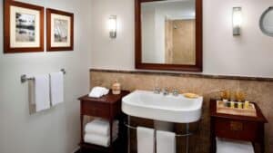 Elegant bathroom with a sink, wooden tables, towels, and framed art at Marriott Mena House.