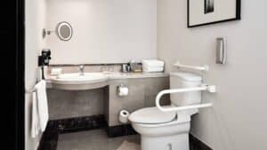Accessible bathroom with grab bars, a toilet, and a wall-mounted sink at Marriott Mena House.