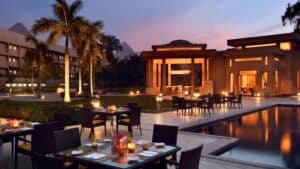 Marriott Mena Houses outdoor dining by the pool at dusk, with lit tables and modern architecture.