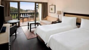 Marriott Mena House offers a room with two beds, a sofa, table, and balcony with outdoor chairs.