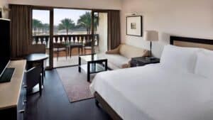 Marriott Mena House room: bed, sofa, table, balcony with palm trees views.