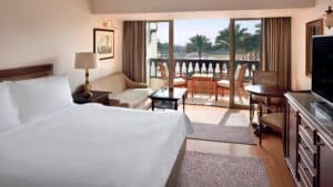Marriott Mena House: Hotel room with bed, sofa, balcony, and palm tree views.