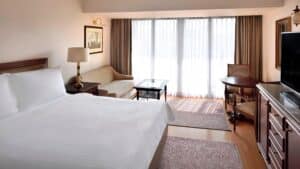 Marriott Mena House room with a bed, sofa, table, chairs, and window with curtains.