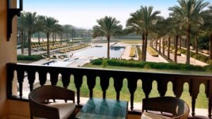 Marriott Mena House balcony with view of resort pool, palm trees, and lounge chairs.