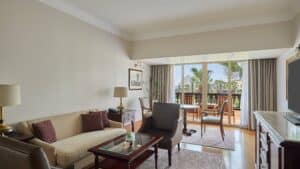 Marriott Mena House room with sofa, armchair, table, and balcony view of palm trees.