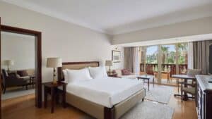 Marriott Mena House room with a bed, seating area, and balcony overlooking palm trees.