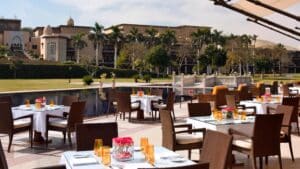 Marriott Mena House offers outdoor dining by the pool, overlooking a garden and buildings.