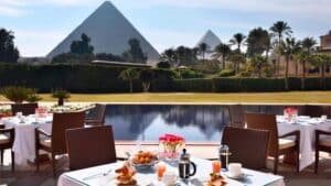Outdoor dining by the pool at Marriott Mena House, with pyramids and palm trees in view.