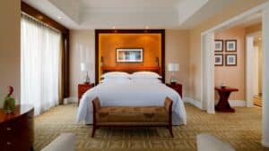 Elegant room at Sheraton Cairo Hotel with king bed, lamps, and art above the headboard.