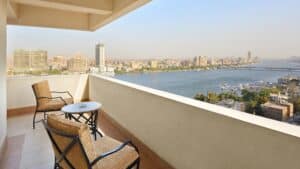 Sheraton Cairos balcony with chairs overlooks a cityscape and the river.