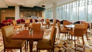 Spacious cafe with wooden tables, red chairs, large windows near Sheraton Cairo Hotel.