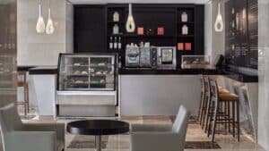 Modern cafe inside Sheraton Cairo with seating, counter, coffee machine, and pastry display.