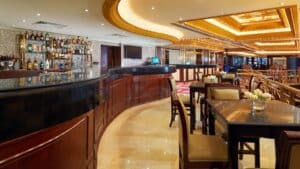 Sheraton Cairos elegant bar features a curved counter, stocked shelves, and cozy tables.