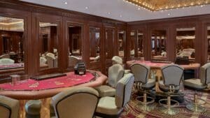 Elegant casino room at Sheraton Cairo with poker tables, mirrored walls, and plush green chairs.