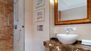 Modern bathroom at Sheraton Cairo Hotel with round sink, marble counter, and glass shower.