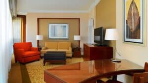 Sheraton Cairo Hotel room: beige sofa, red chair, TV, desk, and framed wall art.
