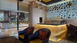 Elegant Sheraton Cairo lounge with woven chairs and a decorative wall behind a polished counter.