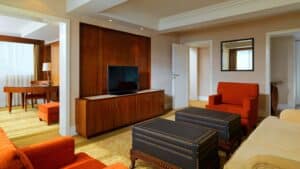 Suite at Sheraton Cairo with TV, orange chairs, ottomans, and a work desk.