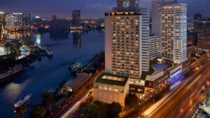 City skyline at night with Sheraton Cairo Hotel, river, tall buildings, and streetlights.
